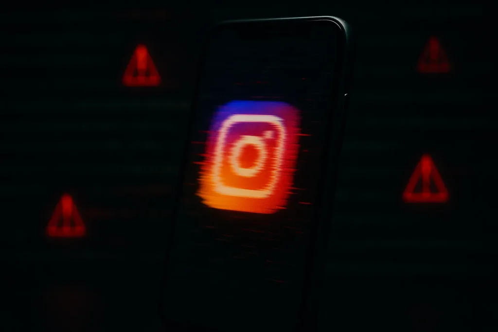 Smartphone exibindo o ícone do Instagram tremendo e desfocado com alertas vermelhos ao fundo